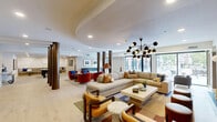 Located at 1220 South Ave in Plainfield, NJ, this thoughtfully designed single-floor amenity space offers a generous and versatile layout across two living areas and a fully equipped kitchen. The first living area is a vibrant lounge anchored by striking bronze cylindrical columns, bold curated artwork, and plush velvet seating in rich terracotta tones accented with cobalt blue cushions. A pool table and built-in banquette seating at the far end make this zone ideal for social gatherings and recreation. The second living area exudes warmth and comfort, featuring an oval tray ceiling with recessed lighting, a multi-bulb statement chandelier, a wall-mounted fireplace set against wood-paneled millwork, and a large sectional sofa. Floor-to-ceiling sliding glass doors flood the room with natural light and open directly to an outdoor patio, seamlessly blending interior and exterior living. The kitchen is anchored by a generously sized curved island with a dark stone countertop and bar seating. White upper cabinetry with arched detailing, open shelving, and a dedicated dining area with a distinctive bronze textured ceiling panel complete the culinary space. Light wood-toned flooring flows consistently throughout, tying the entire space together with a clean, contemporary aesthetic.