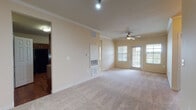 This single-floor residence offers a thoughtfully designed layout that balances functionality and comfort across its living spaces. The open living area is finished with plush wall-to-wall carpeting, crown molding, and a ceiling fan, while a set of glass-paned doors and surrounding windows invite abundant natural light and outdoor views. A wall-mounted HVAC unit ensures year-round climate control.

The kitchen is well-equipped with rich dark wood cabinetry, dark granite-style countertops, hardwood flooring, and a full suite of black appliances including a refrigerator, electric range, built-in microwave, and dishwasher. A pass-through opening connects the kitchen to the living area, enhancing the sense of openness.

The bedrooms are carpeted and generously sized, each featuring ceiling fans and multiple windows for natural light. The primary bedroom includes a private door to the outdoors and access to a walk-in closet. Both bathrooms feature dark wood cabinetry, hardwood flooring, and white countertops. One bathroom includes a tiled tub-shower combination, while the other provides access to a walk-in closet and an in-unit stacked laundry area, adding notable convenience.