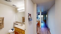Located at 5016 Paseo Padre Parkway in Fremont, CA, this single-floor unit offers a well-organized and functional layout that maximizes every square foot. The open living area features warm wood-style flooring, a textured ceiling, and a sliding glass door that invites natural light while providing access to the outdoors. The space flows naturally from the living area into the kitchen, which is equipped with light wood cabinetry, a smooth-top electric range, a stainless steel dishwasher, a refrigerator, and speckled laminate countertops. A dedicated bar counter with seating connects the kitchen to the living area, creating an open and sociable feel. Notably, the kitchen also houses a stacked washer and dryer unit, adding convenience within the compact footprint. The bathroom is clean and well-appointed, featuring wood-toned cabinetry, a speckled composite vanity countertop, a large wall mirror with overhead lighting, wood-style flooring, and a glass-door shower enclosure. Throughout the unit, the neutral color palette of soft whites and warm tones creates a bright and cohesive ambiance, making this an efficient and comfortable space in the heart of Fremont.