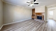Located at 2160 N Thompson Ln in Murfreesboro, TN, this two-story, 2-bedroom, 2-bathroom home is thoughtfully laid out across two floors. The main level offers a living room, dining room, and kitchen. The living room is a standout space, featuring a brick wood-burning fireplace flanked by built-in wooden shelving and cabinetry, crown molding, a ceiling fan, and warm hardwood-style flooring. The dining room continues the refined aesthetic with crown molding, a chandelier, chair-rail detail, and the same hardwood-style flooring. The kitchen is efficiently designed with wood cabinetry, granite-look countertops, and hardwood-style flooring, and is equipped with a range and dishwasher. Upstairs, the two carpeted bedrooms are comfortable and bright, each with a ceiling fan. The primary bedroom is generously sized and features two closets and a window with natural light. Both bathrooms are finished with wood vanity cabinetry, white countertops, and hardwood-style tile flooring. One bathroom features a separate vanity area and private water closet. Throughout the home, neutral tones and consistent finishes create a cohesive and inviting atmosphere.