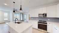 Located on Telluride Street in Denver's 80249 neighborhood, this single-floor residence offers a clean, contemporary design throughout. The open-concept kitchen is a standout feature, outfitted with flat-front white cabinetry extending to the ceiling, a gray tile backsplash, stainless steel appliances including a French door refrigerator, electric range, and built-in microwave. A generously sized white quartz island anchors the space, accented by striking matte black pendant lights and an undermount sink with a matching black faucet. Light wood-tone flooring runs seamlessly throughout the entire unit, adding warmth to the bright, neutral palette. The living area benefits from multiple windows and a ceiling fan, with sightlines that extend to the open Colorado landscape beyond. Bedrooms are well-proportioned, each featuring large windows that invite abundant natural light and outdoor views. The primary bathroom features a dual-sink vanity with white quartz countertops, bold black-framed mirrors, and ample cabinetry below. A second full bathroom offers a tub-shower combination with white tile surround and a single-sink vanity. The overall aesthetic is modern and minimalist, with consistent finishes and a bright, airy atmosphere carried throughout every room.