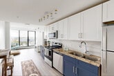 Located at 50-54 Sussex Avenue in Newark, NJ, this one-bedroom, one-bathroom residence offers a well-designed layout that maximizes every square foot. The open-plan kitchen and living area serves as the heart of the home, showcasing a striking two-tone kitchen with white upper cabinetry and navy blue lower cabinets, granite countertops, subway tile backsplash, and a full suite of stainless steel appliances. Light wood-look flooring runs throughout, complementing the clean, bright aesthetic. A dedicated dining area accommodates a bar-height table, adding a functional and stylish touch. The living area is anchored by expansive floor-to-ceiling windows with bold black frames, flooding the space with natural light and offering sweeping panoramic views of the Newark skyline and surrounding cityscape. The bedroom continues the airy feel with its own large window wall framing the same impressive views, along with a sliding-door closet for ample storage. The bathroom features a tub-shower combination with elegant marble-effect wall tile and granite countertops, maintaining the refined finish found throughout the residence. Clean white walls and light flooring create a cohesive, modern ambiance throughout this efficiently planned urban home.