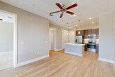 Located at 101 Crawford St in the heart of Houston, TX, this well-appointed one-bedroom, one-bathroom residence offers a thoughtfully designed open-concept layout. Light-toned hardwood-style flooring flows throughout the main living areas, complementing the neutral warm-beige walls and creating a bright, cohesive atmosphere.

The kitchen serves as a centerpiece of the space, featuring a large white-countertop island with an integrated sink, rich dark-brown cabinetry extending to the ceiling, stainless steel appliances including a refrigerator, range, and microwave, a herringbone-patterned tile backsplash, and a built-in beverage cooler. Stylish pendant lights hang above the island, adding a modern touch. The kitchen opens seamlessly into the combined dining and living area, which benefits from natural light and access to an outdoor balcony with views of the Houston skyline.

The bedroom is carpeted for comfort, fitted with a ceiling fan, and offers impressive views of downtown Houston through large windows. It connects directly to the full bathroom, which includes a dual-sink vanity with bold navy-blue cabinetry, a soaking tub, and a separate shower. Two closets provide generous storage, including a walk-in closet with built-in shelving and hanging rods. A dedicated laundry area completes this efficiently designed urban residence.