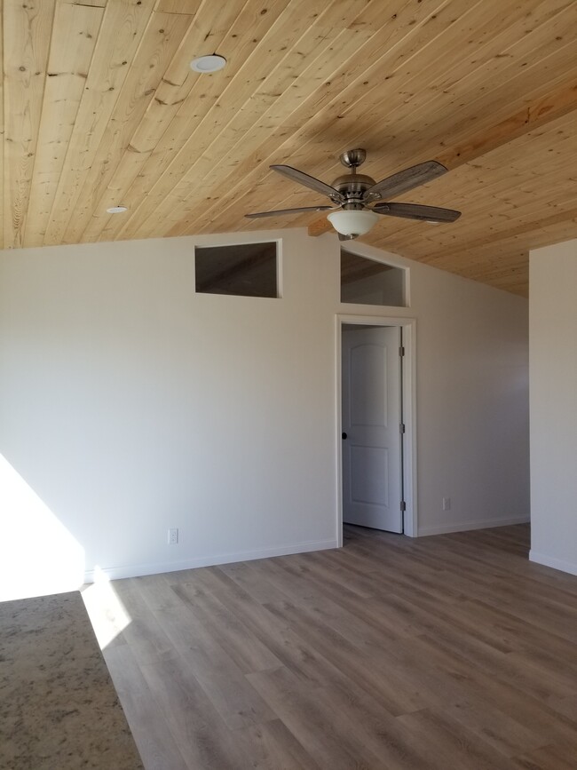 Living room with high wood ceilings, ceiling fan and sliding door to outdoor patio - 6832 Zelzah Ave