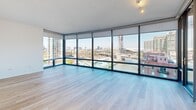 Located in Chicago's vibrant River North neighborhood, this one-bedroom, two-bathroom residence at 520 N Kingsbury Street offers a well-appointed, modern living experience. Light hardwood flooring runs throughout the unit, complementing the clean white walls and creating a bright, cohesive aesthetic.

The open-concept living area is a standout, featuring dramatic floor-to-ceiling windows that wrap the room in natural light and frame sweeping panoramic views of the Chicago skyline. Track lighting adds functionality and a contemporary touch. The living space connects seamlessly to the kitchen, which is outfitted with warm wood cabinetry, stainless steel appliances, a sleek white countertop peninsula, and pendant lighting — all with city views as a backdrop.

The bedroom is generously sized, offering its own floor-to-ceiling window wall with direct access to a private balcony and expansive urban views. An en-suite bathroom provides convenient access from the bedroom. Both bathrooms are finished with large-format tile flooring, wood vanities, white countertops, and full soaking tub and shower combinations.

A well-organized hallway with built-in closets connects the living areas to the private spaces, maintaining a clean and efficient layout throughout this thoughtfully designed urban residence.