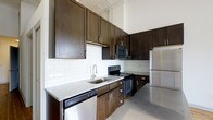 Located at 345 East Deshler Avenue in Columbus, Ohio, this single-floor space combines modern finishes with functional design. The kitchen is a standout feature, showcasing rich dark-espresso cabinetry that extends floor to ceiling, taking full advantage of the impressively tall ceilings. White subway tile backsplash provides a crisp contrast against the cabinetry, while light granite countertops add a refined, elegant touch. A full suite of stainless steel appliances — including a refrigerator, electric range, built-in microwave, and dishwasher — ensures the kitchen is as practical as it is visually striking. Polished concrete-style flooring runs throughout, lending the space an industrial yet contemporary character that complements the overall aesthetic. The soaring ceiling height enhances the sense of openness and airiness, making the space feel expansive and inviting. The thoughtful layout and quality finishes throughout reflect a commitment to both style and functionality, making this Columbus property a compelling and well-rounded living space.