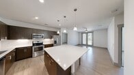 This contemporary 990 square foot apartment offers a thoughtful layout with 2 bedrooms and 3 bathrooms. The heart of the home is an open-concept living area, seamlessly blending the kitchen and living room. The gourmet kitchen boasts dark wood cabinetry, stainless steel appliances, and a sleek white backsplash, complemented by a central island with pendant lighting.

The primary bedroom, measuring 190 square feet, features plush carpeting and ample natural light from large windows. Each bathroom is designed with modern fixtures, including a double vanity in the primary en-suite. The apartment showcases a neutral color palette with light wood-look flooring in main areas and white walls throughout, creating a bright and airy ambiance.

Additional features include ceiling fans for improved air circulation, built-in closets for storage, and a private balcony accessible through sliding glass doors. The property's design emphasizes functionality and style, with recessed lighting and contemporary finishes that appeal to those seeking a modern urban lifestyle.