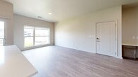 Located at 4007 N Ridge Rd in Wichita, Kansas, this well-appointed 2-bedroom, 2-bathroom residence offers a thoughtfully designed single-level layout with modern finishes throughout. Light-toned wood-look flooring flows through the main living areas, complemented by neutral walls and an abundance of natural light from large windows overlooking outdoor greenery.

The open-concept kitchen is a standout feature, showcasing warm-toned cabinetry with sleek hardware, white quartz countertops, a subway tile backsplash, and stainless steel appliances including a refrigerator and range. A central island with pendant lighting connects the kitchen to the living area, creating an inviting space ideal for entertaining. A sliding glass door provides direct access to a private balcony.

Both bedrooms are carpeted and generously sized, each offering closet access and natural light through large windows. The primary bedroom connects to an en-suite bathroom featuring a wide vanity with white countertop, wood-toned cabinetry, a large mirror, and a linen tower. The second bathroom mirrors this refined aesthetic with similar quality finishes.

A dedicated in-unit laundry room accommodates a full-size washer and dryer side by side. The overall ambiance is clean, contemporary, and move-in ready.
