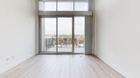 Located at 215 North Pine Street in the heart of uptown Charlotte, NC, this two-story loft combines industrial design with modern finishes across a well-proportioned layout. The lower level features an open-concept kitchen and living area anchored by rich hardwood flooring and exposed ductwork that runs the length of the ceiling, lending an authentic loft aesthetic. The kitchen is outfitted with warm cherry wood cabinetry, granite countertops, a classic subway tile backsplash, and a full suite of stainless steel appliances, including a built-in microwave, electric range, and French door refrigerator. Track lighting overhead provides focused illumination throughout.

The upper level is home to the generously sized primary bedroom, one of the largest features of this space, with polished concrete floors in a deep terracotta tone that carry through the hallways and walk-in closet. The bedroom is bathed in natural light through soaring floor-to-ceiling windows and sliding glass doors that open directly onto a private balcony, offering expansive views of the Charlotte skyline and surrounding cityscape. A ceiling fan provides additional comfort. The spacious walk-in closet features built-in shelving and hanging rods along the full length of the walls. An interior staircase with a sleek metal railing connects both levels seamlessly.