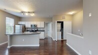 Located at 6460 Chelsea Glen Dr in Columbus, Ohio, this one-bedroom, one-bathroom residence offers a well-designed single-floor layout with a practical and comfortable living environment. The open-concept kitchen and living area serves as the heart of the home, featuring rich hardwood-style flooring that flows throughout. The kitchen is equipped with stainless steel appliances — including a refrigerator, electric range, and microwave — complemented by white cabinetry, dark countertops, and a central island with an integrated sink, providing ample workspace and storage. The living area benefits from multiple windows dressed with blinds, flooding the space with natural light and offering views of the surrounding neighborhood. The bedroom is a comfortable retreat with soft carpeting and a window that continues the theme of natural light. A dedicated walk-in closet with wire shelving provides generous storage. The bathroom features a white vanity with cabinet storage and light tile flooring. Neutral warm-gray tones carry throughout the home, lending a cohesive and move-in-ready aesthetic. The overall layout is efficient and functional, making excellent use of every square foot.