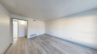 Located at 6555 Lexington Dr in Beaumont, TX, this single-story unit offers three bedrooms and one bathroom across a compact, efficiently designed floor plan. The living room features light-toned wood-look flooring, neutral white walls, a textured ceiling, and a large window near the entry door that allows natural light to fill the space. The galley-style kitchen is well-appointed with gray cabinetry, dark speckled countertops, a built-in sink, electric coil cooktop, and a full-size refrigerator, with ample upper and lower cabinet storage lining both sides of the corridor. The primary bedroom is generously sized, featuring plush carpet, a walk-in closet, and windows that bring in natural light. The two additional bedrooms are also carpeted and include closets, with windows providing outdoor views and natural brightness. The shared full bathroom includes a tub/shower combo with tile surround, a toilet, a vanity with speckled countertop, and overhead cabinetry for storage. Wood-look flooring extends through the hallway, connecting the main areas. The unit also includes a dedicated closet and hallway, rounding out a straightforward and functional layout suitable for everyday living.