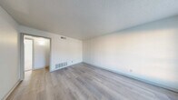 Located at 6555 Lexington Dr in Beaumont, TX, this single-story unit offers three bedrooms and one bathroom across a compact, efficiently designed floor plan. The living room features light-toned wood-look flooring, neutral white walls, a textured ceiling, and a large window near the entry door that allows natural light to fill the space. The galley-style kitchen is well-appointed with gray cabinetry, dark speckled countertops, a built-in sink, electric coil cooktop, and a full-size refrigerator, with ample upper and lower cabinet storage lining both sides of the corridor. The primary bedroom is generously sized, featuring plush carpet, a walk-in closet, and windows that bring in natural light. The two additional bedrooms are also carpeted and include closets, with windows providing outdoor views and natural brightness. The shared full bathroom includes a tub/shower combo with tile surround, a toilet, a vanity with speckled countertop, and overhead cabinetry for storage. Wood-look flooring extends through the hallway, connecting the main areas. The unit also includes a dedicated closet and hallway, rounding out a straightforward and functional layout suitable for everyday living.
