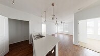 This 2-bedroom, 2-bathroom single-story residence offers a thoughtfully designed open-concept layout. The kitchen serves as the heart of the home, featuring a large peninsula island with a double stainless steel sink, white countertops, and dark espresso cabinetry that extends to the ceiling for ample storage. Pendant lighting and track lighting illuminate the space, while a full suite of appliances — including a refrigerator, range, and dishwasher — adds convenience. The kitchen flows seamlessly into the living area, which is finished with rich hardwood-style flooring, a ceiling fan, and windows with blinds that allow natural light to fill the room. The bedrooms are carpeted for comfort, with one featuring a window with outdoor views. Each bedroom is served by a dedicated closet with wire shelving for organized storage. The two bathrooms are finished consistently with dark wood vanities, white countertops, hardwood-style flooring, and clean white tiling. One bathroom includes a full soaking tub and shower combination, while the other offers a streamlined layout with a wall-mounted cabinet. A utility room rounds out the functional offerings of this well-organized residence.