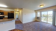 Located at 5501 West Hildebrand Boulevard in Kennewick, Washington, this single-floor unit offers a well-designed, functional layout with a variety of comfortable living spaces. The open-concept living area features plush carpeting, a wall-mounted HVAC unit, and a sliding glass door that leads to a private balcony with outdoor views of the surrounding neighborhood and greenery.

The kitchen is equipped with warm wood cabinetry, dark laminate countertops, and a full suite of black appliances including a refrigerator, range, microwave, and dishwasher. Wood-style flooring runs throughout the kitchen and entry areas, providing a clean contrast to the carpeted living and bedroom spaces.

Multiple bedrooms offer generous natural light through large windows with neighborhood views, ceiling fans for added comfort, and baseboard or wall heating units. Each room provides a calm, neutral atmosphere with cream-toned walls and soft carpeting.

Two bathrooms serve the unit, both featuring rich wood-toned cabinetry, taupe countertops, single-basin sinks, and wood-style flooring. The full bathroom includes a tub-shower combination. Additional storage is available via a walk-in closet visible near the entry area. The overall layout is practical and well-appointed throughout.