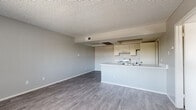 Located at 5312 E Taylor St in Phoenix, Arizona, this single-floor, one-bedroom, one-bathroom unit offers a practical and efficiently designed layout. The open-concept living and kitchen area forms the heart of the space, featuring durable wood-look laminate flooring and neutral gray walls that create a clean, cohesive aesthetic. A textured ceiling runs throughout, adding a classic touch to the interior. The kitchen is well-equipped with white cabinetry, a coil-burner electric range, a full-size refrigerator, and a sink set into a peninsula counter that separates the cooking area from the living space — ideal for casual dining or food prep. The living room is open and versatile, with ample wall space and a window that allows natural light to filter in. The bedroom offers a comfortable retreat with soft carpeting, a window with vertical blinds for privacy and light control, and a dedicated closet for storage. The bathroom is clean and functional, featuring a white vanity with under-cabinet storage, a framed mirror with overhead lighting, a toilet, and a shower/tub combination with wood-look flooring tying the space together. Overall, the unit presents a straightforward, move-in-ready space well-suited for single occupants or couples in the Phoenix area.