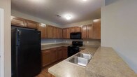 Located at 2753 Michaelsway Ave in Lancaster, Ohio, this single-floor residence offers a functional and comfortable living environment. The kitchen is a standout feature, showcasing warm-toned wooden cabinetry that extends to the upper and lower levels, providing generous storage throughout. Countertops in a neutral laminate finish run along the perimeter and extend into a peninsula, offering additional prep and serving space. The kitchen is equipped with a full suite of black appliances, including a refrigerator, electric range with oven, and an over-the-range microwave. A double-basin stainless steel sink with a modern faucet is conveniently positioned along the peninsula for easy access. The flooring features hardwood-style planks that add warmth to the space. A textured ceiling and flush-mounted lighting complete the kitchen's practical aesthetic. The single-story layout of this residence ensures easy accessibility and a seamless flow between living areas, making it well-suited for a variety of lifestyles. The overall design emphasizes functionality and a cohesive, neutral palette throughout.