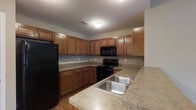 Located at 2753 Michaelsway Ave in Lancaster, Ohio, this single-floor residence offers a functional and comfortable living environment. The kitchen is a standout feature, showcasing warm-toned wooden cabinetry that extends to the upper and lower levels, providing generous storage throughout. Countertops in a neutral laminate finish run along the perimeter and extend into a peninsula, offering additional prep and serving space. The kitchen is equipped with a full suite of black appliances, including a refrigerator, electric range with oven, and an over-the-range microwave. A double-basin stainless steel sink with a modern faucet is conveniently positioned along the peninsula for easy access. The flooring features hardwood-style planks that add warmth to the space. A textured ceiling and flush-mounted lighting complete the kitchen's practical aesthetic. The single-story layout of this residence ensures easy accessibility and a seamless flow between living areas, making it well-suited for a variety of lifestyles. The overall design emphasizes functionality and a cohesive, neutral palette throughout.