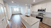This well-appointed two-bedroom, two-bathroom unit at 255 Williamsburg Pkwy in Fate, Texas offers a thoughtfully designed single-level layout. The open-concept kitchen and living area serves as the heart of the home, showcasing granite countertops, a large center island with an undermount sink, white upper cabinetry paired with warm-toned lower cabinets, a subway tile backsplash, and stainless steel appliances including a French door refrigerator and range with over-the-range microwave. Recessed lighting and wood-style plank flooring carry throughout the main living areas, lending a clean, contemporary aesthetic.

Both bedrooms feature plush carpet, ceiling fans, and windows with outdoor views of the surrounding Fate landscape. The primary bedroom connects to a full bathroom with a dual-sink granite vanity, wood-toned cabinetry, a tub-shower combination with white tile surround, and direct access to a generously sized walk-in closet outfitted with multiple hanging rods and built-in shelving. The second bathroom mirrors the refined finishes, and the second bedroom includes its own walk-in closet with wrap-around shelving and hanging storage. The overall ambiance is bright, neutral, and move-in ready.