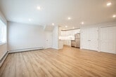 Located at 1019 Spruce Dr in Holbrook, NY, this single-floor unit offers a thoughtfully designed layout with modern finishes throughout. The open living area is anchored by light-toned hardwood-style flooring and recessed lighting, creating a bright and welcoming atmosphere. A large window allows natural light to fill the space, complementing the neutral white walls and clean architectural lines.

The kitchen is well-appointed with white shaker-style cabinetry, white quartz countertops, and a full suite of stainless steel appliances, including a range, microwave, dishwasher, and refrigerator. The seamless backsplash and light flooring give the kitchen a crisp, contemporary feel.

Bedrooms feature plush wall-to-wall carpeting and include closet storage. One bedroom benefits from a window with outdoor views, while another offers angled ceiling detail, adding architectural character. Baseboard heating is present throughout.

The bathroom is finished with a white vanity, quartz countertop, undermount sink, and brushed gold fixtures, conveying a refined, modern aesthetic. A dedicated laundry closet with washer and dryer adds everyday convenience. Additional closet space is accessible off the main living area, rounding out the unit's practical storage offerings.