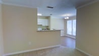 Located at 1525 E Pass Rd in Gulfport, Mississippi, this single-floor residence offers a comfortable and functional layout designed for easy everyday living. The open-concept design connects the kitchen and living areas seamlessly, creating a bright and airy atmosphere throughout.

The kitchen features white cabinetry, a dark granite-style countertop, and a pass-through bar that opens directly to the adjoining living and dining space. A stainless or white appliance suite complements the clean, classic aesthetic of the kitchen. The pass-through design enhances the sense of openness while maintaining a defined cooking area.

The dining and living areas are bathed in natural light, courtesy of large windows fitted with horizontal blinds. An elegant chandelier anchors the dining area, adding a refined touch to the space. The living area features plush carpeting, while the dining space transitions to smooth hardwood-style flooring, offering a pleasant contrast of textures underfoot.

Crown molding runs throughout the home, lending a polished architectural detail that elevates the overall interior. A textured ceiling adds subtle dimension overhead. The warm, neutral wall tones create a welcoming ambiance that complements a variety of décor styles, making this single-floor home both inviting and move-in ready.