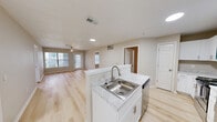 Located at 5230 S ML King Jr Pkwy in Beaumont, Texas, this single-story home offers four bedrooms and four bathrooms within a clean, modern layout. Light-toned hardwood flooring runs throughout the entire space, creating a bright and cohesive aesthetic. The open-concept kitchen and living area serves as the heart of the home, featuring white shaker cabinetry, marble-look countertops, a stainless steel sink, and a full suite of stainless steel appliances including a refrigerator, range, and microwave. A peninsula with additional counter space provides a natural transition into the expansive living room, which benefits from multiple windows and a ceiling fan, filling the area with natural light. Each of the four bedrooms is finished with the same light wood flooring and ceiling fans, and most include sliding-door closets with built-in shelving. The primary bedroom offers direct access to additional rooms and features a window for natural light. The four bathrooms are cleanly appointed with white vanities, modern fixtures, and brushed nickel hardware. The overall design is neutral and move-in ready, with a fresh, contemporary palette throughout.