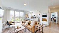 Located at 411 W 8th St in Bloomington, Indiana, this well-appointed one-bedroom, two-bathroom unit offers a thoughtfully designed open-concept floor plan. Light wood flooring flows throughout the space, complementing the bright, white walls and modern finishes that define the interior aesthetic.

The living room is a comfortable and inviting space, highlighted by large sliding glass doors that open onto a private balcony offering open views of the surrounding Bloomington cityscape. Natural light fills the room, creating an airy atmosphere ideal for both relaxing and entertaining.

The kitchen is efficiently laid out with white shaker cabinetry, grey quartz countertops, a classic subway tile backsplash, and stainless steel appliances including a refrigerator, range, microwave, and dishwasher. A peninsula with bar seating and pendant lighting above adds both function and style, seamlessly connecting the kitchen to the living area.

The bedroom is a well-sized, private retreat featuring a window with natural light, and ample space for a full furniture arrangement. Two closets provide generous storage throughout the unit.

Both bathrooms are finished with white cabinetry, grey countertops, and full tub-shower combinations, maintaining the clean, modern style found throughout the rest of the space.
