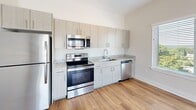 Located at 30 Market St SW in Concord, NC, this well-designed 2-bedroom, 2-bathroom residence offers a thoughtfully organized single-level layout. The open-concept living and kitchen area serves as the heart of the home, featuring warm hardwood-style flooring and bright, neutral walls that create a clean and welcoming atmosphere. Large windows and a set of glass doors in the living room flood the space with natural light and provide direct access to a private balcony with outdoor views.

The kitchen is equipped with stainless steel appliances — including a refrigerator, range, microwave, and dishwasher — complemented by granite-style countertops and contemporary light wood cabinetry that extends to the ceiling for ample storage. A functional hallway connects the main living areas to the two bedrooms, each finished with plush carpet flooring and neutral tones that offer a comfortable, restful environment. The generously sized primary bedroom includes a walk-in closet outfitted with multi-tiered wire shelving for versatile organization.

Both bathrooms are finished with hardwood-style flooring and feature clean, modern fixtures, including a full tub-shower combination. Two closets throughout the unit provide practical storage solutions. The overall aesthetic is modern and understated, making this a move-in-ready residence in the heart of Concord.