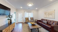 This well-appointed 2-bedroom, 2-bathroom residence in Jonesboro, Arkansas delivers a comfortable and functional single-floor layout with consistent, modern finishes throughout. Rich hardwood-style flooring flows seamlessly across all living areas, anchoring the home's warm, cohesive aesthetic.

The living room features crown molding, recessed lighting, and a flush-mount ceiling fixture, with natural light streaming in through multiple windows dressed with classic blinds. Adjacent to the living area, the dining room is highlighted by an elegant chandelier, neutral walls, and ample space for a full dining set — ideal for everyday meals or entertaining.

The kitchen is a standout, boasting crisp white shaker cabinetry, a white quartz island, subway tile backsplash, and a full suite of stainless steel appliances including a French door refrigerator and electric range with over-the-range microwave.

Both bedrooms are generously sized, each featuring ceiling fans with lighting, natural window light, and a neutral color palette. The primary bathroom includes a white vanity with dark hardware accents and a tiled shower/tub combination, while the second bathroom mirrors the same refined style. A dedicated in-unit laundry room with full-size washer and dryer connections adds everyday convenience to this move-in-ready home.