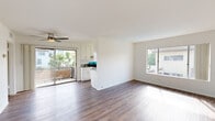 This thoughtfully designed single-floor residence offers a comfortable and functional layout across five distinct spaces: a living room, bedroom, kitchen, bathroom, and hallway. Rich hardwood-style flooring flows throughout, lending a warm and cohesive feel to the entire unit.

The open living area is bright and airy, benefiting from multiple sliding windows and a sliding glass door that leads to a private balcony with views of lush greenery. A ceiling fan adds to the comfort of the space. The galley-style kitchen is efficiently designed with white shaker cabinetry, granite-look countertops, a stainless steel double sink, a gas range, and a dishwasher, all illuminated by natural light from a window with blinds.

The bedroom is a well-proportioned retreat featuring hardwood-style flooring, a ceiling fan, a large sliding-door closet with built-in shelving, and a window that brings in natural light. The bathroom is clean and simply appointed, with a full tub-shower combination, chrome fixtures, and a window for ventilation and natural light.

Throughout the space, the consistent use of white walls, wood-tone flooring, and natural light creates a bright, neutral, and inviting atmosphere suited for everyday living.