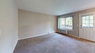 Located at 630 Oaklawn Ave in Cranston, Rhode Island, this single-floor residence offers a well-organized layout with a variety of functional living spaces. The entryway welcomes you with light tile flooring and a ceiling fan overhead, with direct sightlines into both the living area and kitchen. The living room is carpeted and filled with natural light from a large sliding window that opens to a private balcony, offering pleasant outdoor views of surrounding greenery. A separate room features warm hardwood flooring, a window with natural light, and a generous walk-in closet, making it well-suited as a bedroom. An additional room with polished hardwood floors provides flexible use as a second bedroom or office space. The galley-style kitchen is efficiently designed with rich wood cabinetry, granite-style countertops, tile flooring, and white appliances including a range, microwave, and refrigerator. The bathroom is clean and bright, appointed with tile flooring, white cabinetry, a vanity with a large mirror, and baseboard heating. Throughout the unit, neutral wall tones and baseboard heating systems contribute to a cohesive and comfortable atmosphere. The space offers a practical and inviting environment suited for everyday living.