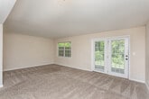 Located in Macon, GA (31210), this two-floor home offers a practical and well-organized layout across both levels. The kitchen is equipped with white cabinetry, granite-style countertops, and black appliances including a range, dishwasher, and refrigerator, all complemented by warm hardwood flooring. A hallway off the kitchen leads to a full bathroom featuring wood-look tile flooring, a vanity with white cabinetry, and a tub-shower combination. The main living area is carpeted and generously proportioned, with large windows and a set of French doors that invite abundant natural light and provide outdoor access. Multiple bedrooms are spread across both floors, each featuring plush carpet, ceiling fans or light fixtures, and windows with views of surrounding greenery. Several bedrooms include built-in closets with shelving. The upper floor is accessed via a carpeted staircase and features a hallway connecting additional bedrooms and a bathroom with a white vanity and well-lit mirror. Throughout the home, neutral wall tones, white trim, and consistent finishes create a clean, cohesive aesthetic that offers a versatile and move-in-ready living environment.