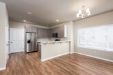 Located at 4321 Briggs Dr SE in Olympia, Washington, this two-story home offers a thoughtfully designed layout with modern finishes throughout. The main level features generously sized living and dining areas bathed in natural light from large windows with blinds, all unified by warm-toned hardwood-style flooring. A chandelier anchors the dining area, adding a refined touch to the open space.

The kitchen is well-equipped with contemporary wood-grain cabinetry, light stone countertops, stainless steel appliances including a refrigerator with ice maker, electric range, and built-in microwave. A breakfast bar with seating provides a casual dining option, while an adjacent window brings in additional natural light. A convenient half bath is accessible on the main level.

Upper living areas transition to plush carpeting in the bedrooms, which include sliding and hinged closet doors offering ample storage. The bathrooms are finished with stone-topped vanities and tiled tub-shower combinations, with one featuring large-format wall tile and a built-in niche. A dedicated laundry room houses a full-size washer and dryer beneath upper cabinetry, adding everyday convenience. Throughout, neutral tones and clean lines create a bright, functional, and welcoming living environment.