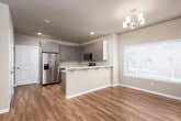 Located at 4321 Briggs Dr SE in Olympia, Washington, this two-story home offers a thoughtfully designed layout with modern finishes throughout. The main level features generously sized living and dining areas bathed in natural light from large windows with blinds, all unified by warm-toned hardwood-style flooring. A chandelier anchors the dining area, adding a refined touch to the open space.

The kitchen is well-equipped with contemporary wood-grain cabinetry, light stone countertops, stainless steel appliances including a refrigerator with ice maker, electric range, and built-in microwave. A breakfast bar with seating provides a casual dining option, while an adjacent window brings in additional natural light. A convenient half bath is accessible on the main level.

Upper living areas transition to plush carpeting in the bedrooms, which include sliding and hinged closet doors offering ample storage. The bathrooms are finished with stone-topped vanities and tiled tub-shower combinations, with one featuring large-format wall tile and a built-in niche. A dedicated laundry room houses a full-size washer and dryer beneath upper cabinetry, adding everyday convenience. Throughout, neutral tones and clean lines create a bright, functional, and welcoming living environment.