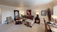 This single-floor two-bedroom, one-bathroom residence features a thoughtfully arranged layout that balances comfort and functionality throughout. The living room is a welcoming centerpiece, finished with plush carpeting, crown molding, and a large window that invites natural light and views of the surrounding greenery. The dining area sits adjacent, illuminated by a ceiling fixture and fitted with vertical blinds for adjustable light control. The galley-style kitchen is efficiently organized, featuring white cabinetry with ample storage, granite-style countertops, a double sink, and white appliances including a range, microwave, and refrigerator, all complemented by hardwood-style flooring. The primary bedroom offers carpeted floors, a closet with built-in shelving, and warm, neutral tones that create a restful atmosphere. The second bedroom provides flexible use, with carpeted floors and a window allowing natural light. The shared full bathroom includes a vanity with a white sink, a mirror with overhead lighting, and a shower-tub combination. Crown molding and consistent neutral tones throughout the residence contribute to a cohesive and polished aesthetic.