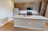 This 1,090-square-foot single-floor apartment in Lawrenceville, GA offers 2 bedrooms, 2 bathrooms, and 2 closets within a thoughtfully designed layout. The open-concept kitchen and living area serves as the heart of the unit, featuring wood-toned cabinetry, granite countertops, a white subway tile backsplash, and stainless steel appliances including a refrigerator, range, and microwave. A large kitchen island with an integrated sink adds both functionality and additional counter space. Light hardwood-style flooring extends through the main living areas, complemented by a ceiling fan and abundant natural light from multiple windows with blinds. Both bedrooms are carpeted and well-lit, each featuring ceiling fans and windows with outdoor views of surrounding greenery. The primary bedroom measures 160 square feet. Both bathrooms mirror each other in design, offering wood-toned vanity cabinetry, granite countertops, large mirrors, and light hardwood-style flooring. The primary bath includes a walk-in glass-enclosed shower, while the secondary bath offers a tub/shower combination. Neutral wall tones and consistent modern finishes create a cohesive, move-in-ready aesthetic throughout the entire unit.