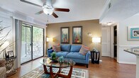 This single-floor, two-bedroom, two-bathroom residence at The Abbys At Inverness in Birmingham, Alabama, offers a well-designed layout that balances comfort and functionality. The living room serves as the central gathering space, featuring hardwood-style flooring, crown molding, a textured ceiling with a ceiling fan, and a bold blue-gray accent wall. A large sliding glass door floods the room with natural light and opens directly onto a private balcony with outdoor views of surrounding greenery, creating a seamless indoor-outdoor connection.

The kitchen is equipped with stainless steel appliances, including a range and over-the-range microwave, complemented by dark espresso cabinetry, granite-style countertops, and a classic white subway tile backsplash. Both bedrooms feature plush carpeting and ceiling light fixtures. One bedroom showcases a warm yellow accent wall, while the second features neutral tones with ample natural light from a large window.

Each of the two bathrooms is finished with dark wood vanity cabinetry, granite-style countertops, and tile flooring. One bathroom features a tub-shower combination, while the other offers a spacious vanity area. Together, these rooms create a cohesive, modern living environment with consistent, quality finishes throughout.
