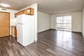 This single-floor unit offers a practical and functional layout designed to maximize usable living space. The open-concept living and dining area flows directly into the kitchen, creating a cohesive, connected feel. Durable wood-look vinyl plank flooring runs throughout the main living spaces, while a ceiling fan provides both light and air circulation. A full-width sliding glass door fitted with vertical blinds leads to a private outdoor patio, drawing in natural light and providing outdoor access.

The kitchen is equipped with warm-toned wooden cabinetry, a white refrigerator, an electric range, a dishwasher, and a sink with dark laminate countertops. Overhead cabinets offer ample storage, and under-cabinet lighting adds functional illumination to the workspace.

Two bedrooms are finished with plush wall-to-wall carpeting and textured ceilings. Each room features a window with blinds for natural light and privacy. One bedroom includes dual closets, one of which is a walk-in, providing generous storage capacity.

The full bathroom includes a single-sink vanity with wooden cabinetry, a toilet, and a tub-shower combination with a white surround. Wood-look flooring ties the bathroom's design together with the rest of the unit, contributing to a cohesive overall aesthetic.