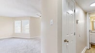Located in Irving, TX, this one-bedroom, two-bathroom residence offers a thoughtfully arranged single-floor layout across a compact yet functional footprint. The living room features plush carpeting, neutral warm-toned walls, and a ceiling fan, with a window fitted with horizontal blinds that filters in natural light. The kitchen is well-appointed with white shaker-style cabinetry, granite countertops, a tile backsplash, wood-look flooring, and black appliances including a refrigerator and electric range, providing ample storage and prep space. The bedroom is carpeted and comfortably sized, featuring a large window that brings in generous natural light and direct access to a dedicated walk-in closet complete with built-in shelving and hanging rods. Both bathrooms are finished with wood-look tile flooring. The primary bathroom includes a white vanity with granite countertops, a framed mirror, and a separate water closet, while the second bathroom features a full soaking tub with white tile surround and a built-in niche. A hallway connects the rooms, maintaining a clean and efficient flow throughout the space. The overall aesthetic is bright, clean, and move-in ready.
