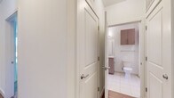 Located at 11500 Commerce Park Dr in Reston, Virginia, this modern single-floor residence offers a thoughtfully designed layout with contemporary finishes throughout. The open-concept living and kitchen area serves as the heart of the home, showcasing wide-plank hardwood-style flooring, crisp white walls, and an abundance of natural light streaming through oversized windows dressed with horizontal blinds. The kitchen is a standout feature, equipped with stainless steel appliances including a refrigerator, range, and over-the-range microwave, complemented by white cabinetry, a subway tile backsplash, and a central island with a dark granite countertop and an integrated sink — ideal for both cooking and casual dining. Track lighting above the kitchen adds a modern touch. The bedrooms offer plush carpeting, clean white walls, and windows that frame outdoor views, creating bright and comfortable retreats. The bathrooms are finished with light wood-toned cabinetry, marble-look countertops, white tile flooring, and full tub-shower combinations with large-format white tile surrounds. The overall aesthetic is clean, contemporary, and move-in ready, reflecting a cohesive modern design sensibility throughout the entire residence.
