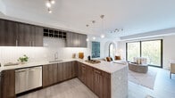 This thoughtfully designed 1-bedroom, 2-bathroom residence offers a seamless blend of modern aesthetics and functional living across a single floor. The open-concept kitchen and living area serves as the heart of the home, where rich walnut-toned cabinetry, a herringbone tile backsplash, and a striking marble-topped island with bar seating create a sophisticated culinary space. Pendant lighting and integrated wine storage add refined detail, while stainless steel appliances complete the kitchen's contemporary appeal. The living area flows naturally from the kitchen, anchored by large floor-to-ceiling windows and a sliding glass door that flood the space with natural light and offer views of surrounding greenery. A distinctive arched architectural detail adds a touch of character to the open layout. The primary bedroom is a serene retreat, highlighted by an eye-catching teal accent wall, plush carpeting, generous walk-in closet space, and expansive windows that invite ample daylight. Both bathrooms are finished with large-format tile flooring, floating wood vanities, and clean, modern fixtures. Light wood-style flooring runs throughout the main living areas, tying together a cohesive and inviting design that balances warmth with contemporary sophistication.