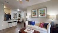 Located at 16303 Chelsea Place in Selma, Texas, this single-floor residence offers a thoughtfully designed layout that balances comfort and functionality. The living area serves as the heart of the home, featuring rich hardwood-style flooring, vaulted ceilings, and a ceiling fan that enhances airflow and ambiance. A glass-panel door opens to a private balcony, filling the space with natural light and offering views of the surrounding greenery. The open-concept design flows seamlessly into a dining area, creating an inviting space for entertaining. A breakfast bar with counter seating bridges the living and kitchen spaces. The galley-style kitchen is well-equipped with dark granite countertops, gray cabinetry, and black appliances, including a range, microwave, and refrigerator. An in-unit laundry area is conveniently accessible from the kitchen. The bedroom is a tranquil retreat with plush carpeting, a large window overlooking the outdoors, vaulted ceilings, and a spacious walk-in closet with built-in shelving. The bathroom features dark granite countertops, gray cabinetry, a wide vanity mirror, and a shower-tub combination, maintaining the cohesive design aesthetic found throughout the residence.