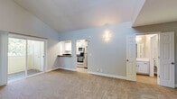 Located at 3644 Kings Way in Sacramento, CA, this single-floor unit offers a well-organized layout across a compact yet functional footprint. The living room is a standout space, characterized by dramatic vaulted ceilings that amplify the sense of openness and volume. Soft, neutral carpet covers the living area floor, while a high transom window draws in natural light. A sliding glass door connects the living space to a private balcony, offering a pleasant outdoor retreat with views of surrounding greenery.

The kitchen is efficiently designed and flows directly off the living area, featuring white cabinetry with modern hardware, dark countertops, a stainless steel sink, and a suite of appliances including a stainless steel refrigerator, electric range, and built-in microwave. Light wood-tone flooring grounds the kitchen with a clean, contemporary feel.

The unit includes two bathrooms, both finished in a bright, neutral palette. One bathroom features a white vanity with a square undermount sink and a large mirror, while the other includes a full tub-and-shower combination with wood-look tile flooring. A dedicated closet provides additional storage, completing this tidy and practical residential space.