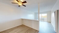 Located at 14950 Zelma St in San Leandro, CA, this 2-bedroom, 1-bathroom residence offers a thoughtfully laid-out single-floor plan. Light-toned wood-style flooring runs consistently throughout the home, creating a clean and cohesive aesthetic. A central hallway connects the main living areas to the private bedrooms, each of which features bright white walls, natural light from sizable windows with views of surrounding greenery, and ample closet space — four closets are distributed across the unit.

The combined living and dining area is a standout feature, highlighted by a ceiling fan, a textured ceiling, and a low half-wall partition that defines the dining space while maintaining an open feel. A large sliding glass door floods the area with natural light and provides outdoor access. The kitchen is efficiently designed in a U-shaped layout with white cabinetry, subway tile backsplash, a range with overhead hood, a refrigerator, and a window above the sink.

The primary bedroom is comfortably sized, offering tree-lined views through its window. The second bedroom is similarly bright and well-proportioned. The bathroom is finished with a full tub-shower combination, white tile surround, a vanity with white cabinetry, and wood-style flooring.