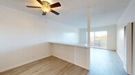 Located at 14950 Zelma St in San Leandro, CA, this 2-bedroom, 1-bathroom residence offers a thoughtfully laid-out single-floor plan. Light-toned wood-style flooring runs consistently throughout the home, creating a clean and cohesive aesthetic. A central hallway connects the main living areas to the private bedrooms, each of which features bright white walls, natural light from sizable windows with views of surrounding greenery, and ample closet space — four closets are distributed across the unit.

The combined living and dining area is a standout feature, highlighted by a ceiling fan, a textured ceiling, and a low half-wall partition that defines the dining space while maintaining an open feel. A large sliding glass door floods the area with natural light and provides outdoor access. The kitchen is efficiently designed in a U-shaped layout with white cabinetry, subway tile backsplash, a range with overhead hood, a refrigerator, and a window above the sink.

The primary bedroom is comfortably sized, offering tree-lined views through its window. The second bedroom is similarly bright and well-proportioned. The bathroom is finished with a full tub-shower combination, white tile surround, a vanity with white cabinetry, and wood-style flooring.
