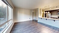 Located in Kirkland, WA, this well-appointed 2-bedroom, 2-bathroom residence offers a thoughtfully designed single-floor layout. The open-concept kitchen and living area serves as the heart of the home, featuring rich dark cabinetry, granite countertops, a large kitchen island with pendant lighting, stainless steel appliances including a refrigerator, range, and microwave, and hardwood-style flooring throughout. Track lighting and natural light from large windows create a bright, welcoming atmosphere in the living space.

The two bedrooms are comfortably sized, with soft carpeting underfoot and windows that let in natural light and offer views of the surrounding trees and neighborhood. Three closets provide ample storage throughout the residence. A dedicated laundry area adds everyday convenience.

Both bathrooms are finished with granite-topped dark vanities, wood-look flooring, and modern fixtures. One bathroom includes a walk-in shower with sliding glass doors, while the other offers a clean, functional layout with a full vanity and mirror. A hallway connects the private areas of the home to the main living spaces, and a welcoming entrance completes the floor plan. The overall aesthetic is clean, modern, and move-in ready.