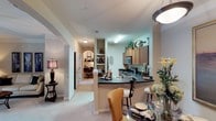 Located at 3801 Glen Verde Trl in Raleigh, NC, this single-floor residence offers a thoughtfully designed layout with a seamless flow between living, dining, and kitchen spaces. The kitchen is well-equipped with warm wood cabinetry, dark granite-style countertops, stainless steel appliances including a range and microwave, a double-basin sink, and a breakfast bar that opens to the dining area. The adjacent dining space features a pendant light fixture and connects naturally to the kitchen for convenient entertaining. The living room is carpeted and bright, with crown molding, a ceiling fan, and a sliding glass door that opens to a private outdoor patio. The primary bedroom is generously sized with plush carpet, ample dresser space, and direct access to a full bathroom. A second bedroom provides comfortable proportions with a ceiling fan and easy access to the hallway. Both bathrooms are finished with dark countertops, wood-toned cabinetry, and tub-shower combinations. A hallway with built-in shelving and an arched architectural detail adds character and connects the living spaces cohesively. Throughout, the warm neutral color palette and consistent finishes create a welcoming and functional living environment.