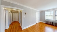 Located at 357 S Harvey Ave in Oak Park, Illinois, this single-floor unit showcases a cohesive blend of classic architectural character and functional design. Warm-toned hardwood floors extend throughout the living areas and bedrooms, complemented by crisp white crown molding and baseboards that add a refined, traditional feel to each room.

The main living area is generously proportioned, with multiple windows allowing ample natural light to fill the space. A bay window configuration in one area further enhances the brightness, offering pleasant outdoor views. A cast-iron radiator serves as both a functional heating element and a nod to the building's historic character. Ceiling fans in the bedrooms provide additional comfort and air circulation.

The kitchen is equipped with white cabinetry, dark laminate countertops, a stainless steel sink, and a gas range with an overhead ventilation hood. The layout is efficient and practical. The bathroom features light tile flooring, a pedestal-style sink with a dark-framed mirror, a tub-shower combination with a curtain, and a radiator. Throughout the unit, neutral gray walls provide a clean, versatile backdrop. The overall ambiance is bright, classic, and well-maintained.
