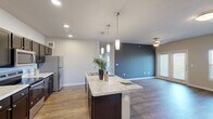 Located near McKinney Falls Parkway in Austin, TX, this single-story, 4-bedroom, 2-bathroom home offers a well-designed open-concept layout. The combined kitchen and living area forms the heart of the home, featuring rich wood-look flooring, recessed lighting, and a striking dark accent wall that adds depth to the space. The kitchen is appointed with dark cabinetry, granite-look countertops, stainless steel appliances, and a large center island with pendant lighting and a built-in sink — ideal for both cooking and casual dining. The living area is bright and open, with a ceiling fan and sliding French doors that flood the room with natural light and provide outdoor views. Each of the four bedrooms is carpeted for comfort and includes a ceiling fan and windows with natural light. The primary bedroom is generously sized and connects to a well-appointed bathroom featuring a dual-sink vanity with marble-look countertops, dark cabinetry, and large-format tile shower surround. A dedicated walk-in closet with wire shelving provides ample storage. The neutral color palette, consistent finishes, and practical layout make this home a comfortable and functional living space.