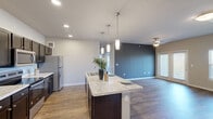 Located near McKinney Falls Parkway in Austin, TX, this single-story, 4-bedroom, 2-bathroom home offers a well-designed open-concept layout. The combined kitchen and living area forms the heart of the home, featuring rich wood-look flooring, recessed lighting, and a striking dark accent wall that adds depth to the space. The kitchen is appointed with dark cabinetry, granite-look countertops, stainless steel appliances, and a large center island with pendant lighting and a built-in sink — ideal for both cooking and casual dining. The living area is bright and open, with a ceiling fan and sliding French doors that flood the room with natural light and provide outdoor views. Each of the four bedrooms is carpeted for comfort and includes a ceiling fan and windows with natural light. The primary bedroom is generously sized and connects to a well-appointed bathroom featuring a dual-sink vanity with marble-look countertops, dark cabinetry, and large-format tile shower surround. A dedicated walk-in closet with wire shelving provides ample storage. The neutral color palette, consistent finishes, and practical layout make this home a comfortable and functional living space.