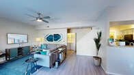 Located in Phoenix, AZ, this two-story home offers three bedrooms and three bathrooms thoughtfully distributed across two well-proportioned floors. The main level features an open-concept living room and kitchen, where light wood-look flooring and neutral walls create a bright, welcoming atmosphere. A ceiling fan overhead and sliding glass door leading to the outdoors enhance the living area's airy feel, complemented by built-in shelving for additional storage and display. The kitchen is equipped with stainless steel appliances, white cabinetry, granite-style countertops, and a convenient pass-through breakfast bar that connects seamlessly to the living space. In-unit laundry is accessible directly from the main living area. The bathrooms feature clean, modern finishes, including a stylish vessel sink with a dark countertop and round mirror on the lower level, and a full tub-shower combination on the upper floor. Each bedroom is carpeted and benefits from natural light through wide windows, with ceiling fans providing comfort. The bedrooms offer ample closet storage, and two dedicated closet spaces serve the home. The overall design is clean and contemporary, with a cohesive neutral palette accented by teal tones visible throughout the space.